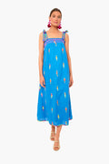 A woman in a bright blue sleeveless organic cotton dress with colorful figures and tied straps from Nimo With Love, paired with nude sandals for a breezy, beachy look.