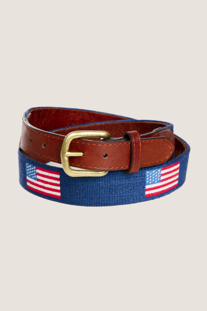 American Flag Needlepoint Belt with classic U.S. flag motifs on blue needlepoint fabric, brown leather trim, and brass buckle, offering an effortless and fun high-end style.