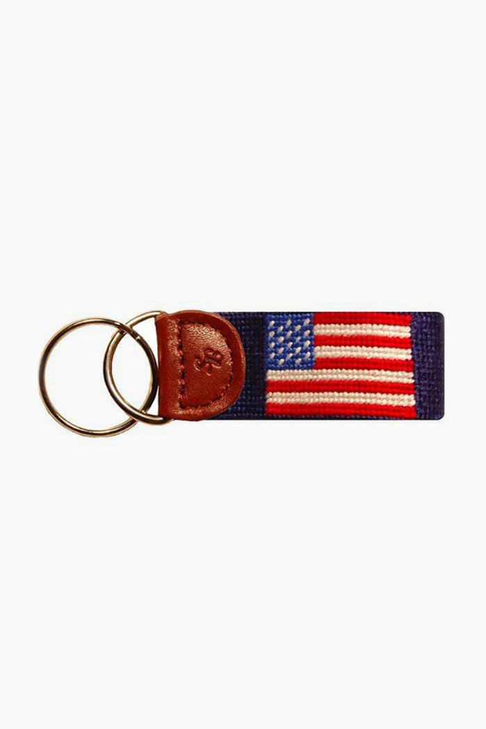 A Smathers and Branson keychain, hand-stitched with an American flag needlepoint design, features a leather accent and two metal key rings.