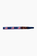 A navy blue fabric belt by Smathers and Branson, featuring hand-stitched American Flag needlepoint designs and a brown leather accent.