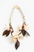 A statement necklace from Weekend Max Mara with cream flower-shaped beads, brown leaf-shaped beads, gold metal links, and a white cord in a floral design.