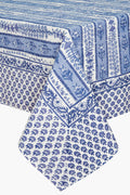 A rectangular table adorned with a blue and white Couleur Nature Paris French tablecloth, featuring handmade linen and botanical designs.