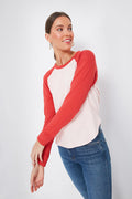 Woman in a red and white retro Faherty baseball tee with blue jeans, looking to the side. This pima cotton long sleeve combines comfort, style, and sustainability for a modern update on a classic.