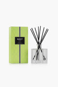 The NEST New York Bamboo Reed Diffuser pairs a green patterned box with a clear glass bottle and black diffuser sticks, elevating your home fragrance experience.