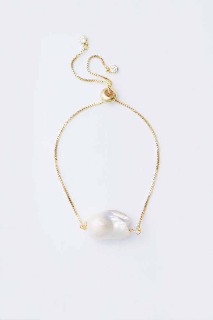 Neely Phelan gold chain statement bracelet with adjustable length, featuring a large irregular white Baroque pearl centerpiece.