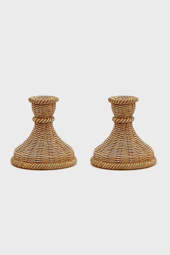 A pair of woven rattan candle holders by Two's Company, featuring wide bases and flared tops—ideal for bringing coastal charm to your home decor.