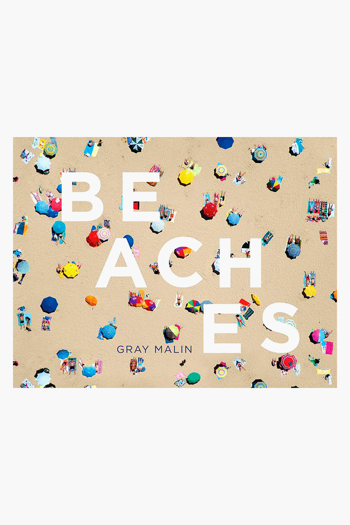 Aerial view of a crowded sandy beach with colorful umbrellas and towels, overlaid with large white text reading BEACHES and Gray Malin's name below—an eye-catching Rizzoli coffee table book featuring stunning aerial beach photography.