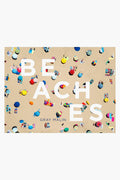 Aerial view of a crowded sandy beach with colorful umbrellas and towels, overlaid with large white text reading BEACHES and Gray Malin's name below—an eye-catching Rizzoli coffee table book featuring stunning aerial beach photography.
