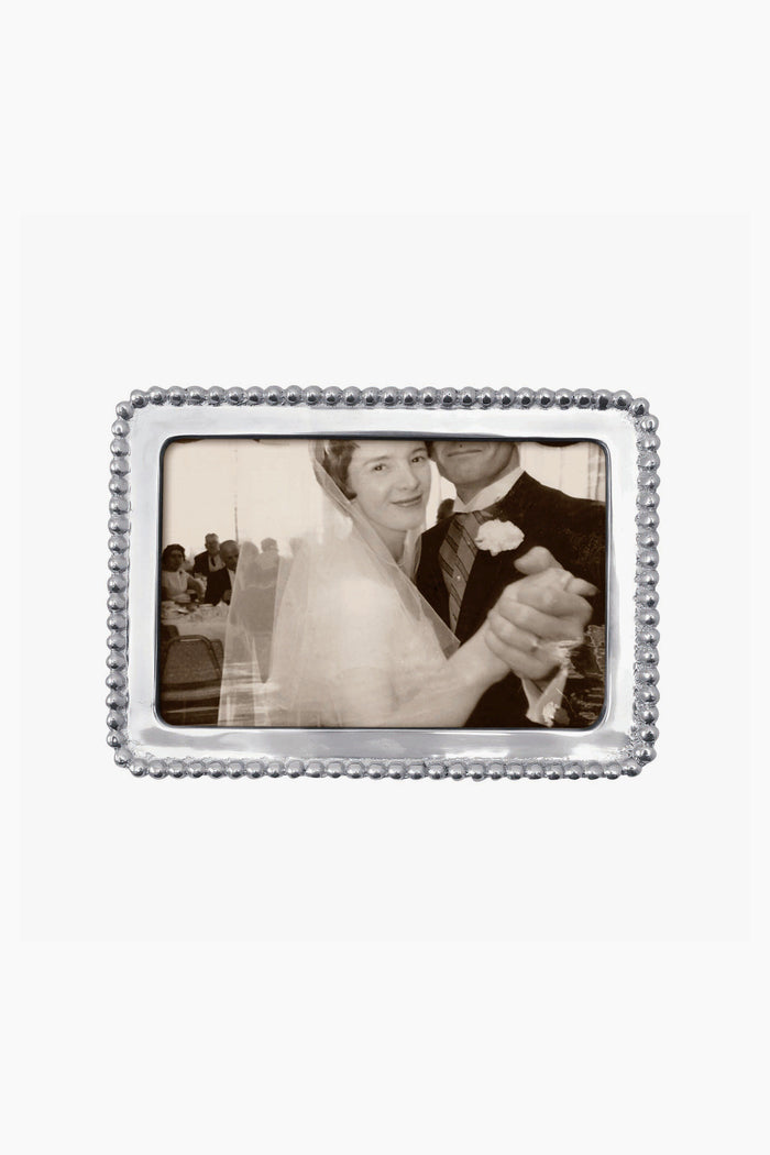 A black and white photo of a bride and groom dancing, with the groom’s face partially out of view, displayed in a Mariposa beaded recycled aluminum frame.