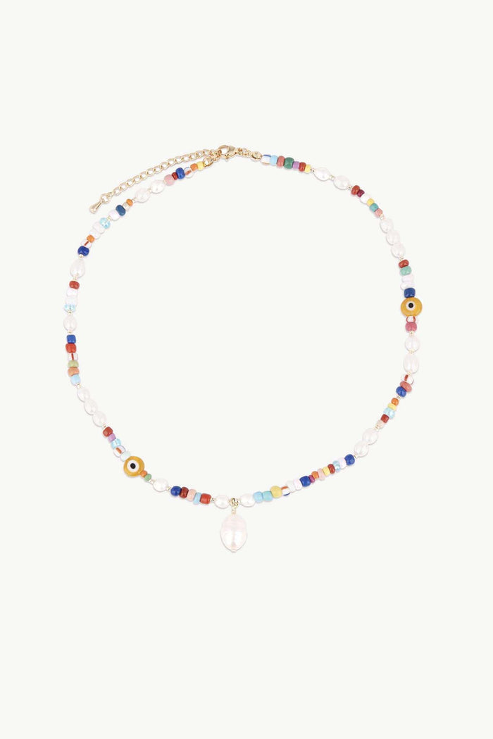 Beaded Multi Pearl Drop Necklace by Petit Moments features colorful beads, clear rounds, a teardrop pendant center, and is finished with a gold clasp and adjustable chain. From a woman-owned brand.