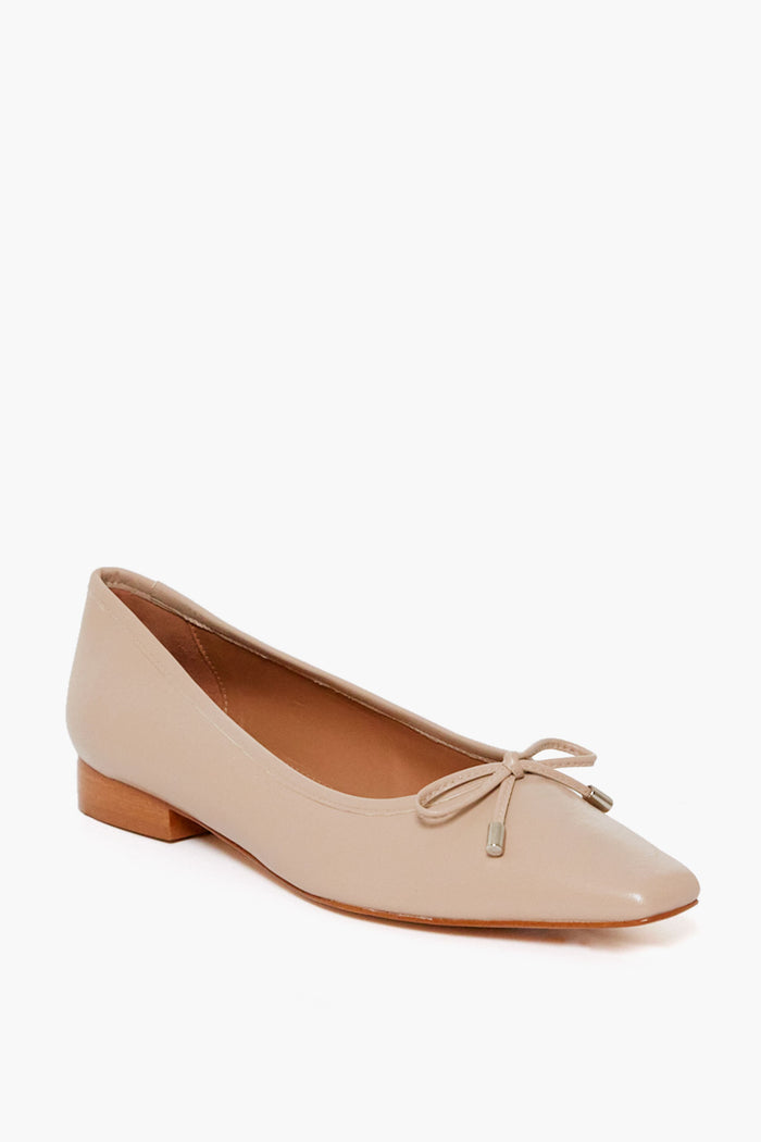 Flattered's beige leather ballet flat features a small wooden heel and a bow on the rounded toe, offering a stylish handmade shoe option.