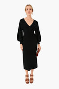 A woman wears a STAUD Black Carnation sweater midi dress featuring long sleeves and a V-neck, paired with brown platform sandals, statement earrings, and holding a small brown clutch.