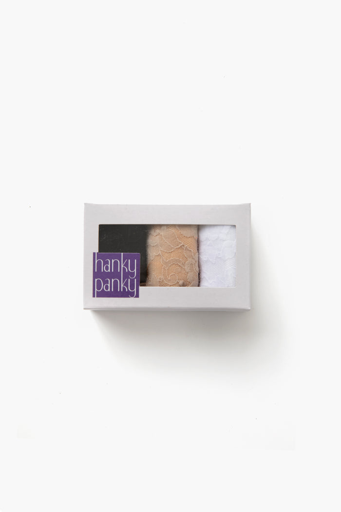 The Hanky Panky boxed set includes three low-rise lace thongs in black, beige, and white, packaged in a white box with a transparent window for a no visible panty line look.