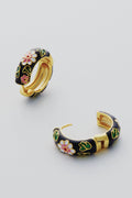 Petit Moments’ Black Deco Hoops are gold-plated with black enamel, adorned with pink and white flowers and green leaves, adding a touch of floral elegance to any look.