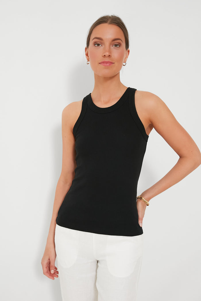 A woman wears the Alex Mill black ribbed tank—a perfect closet staple—paired with white pants. Her hair is pulled back and she completes the look with minimal jewelry.