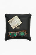 A black leather catchall tray by Graphic Image holds a folded twenty-dollar bill, a credit card, and brown sunglasses with green-tinted lenses.