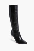 A single black leather knee-high boot by Schutz is shown, featuring a pointed toe and a high stiletto heel.