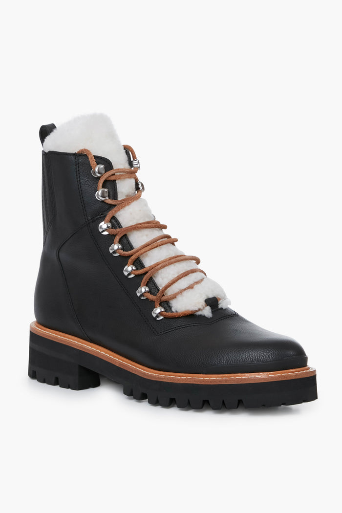 Marc Fisher black leather lace-up winter boots featuring a thick lug sole, metal eyelets, brown laces, and white shearling lining on the tongue and collar.