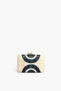 The Kayu rectangular straw clutch features a geometric dark blue and cream pattern and a clasp closure with two round beige knobs. This stylish accessory is part of our sustainable collection.