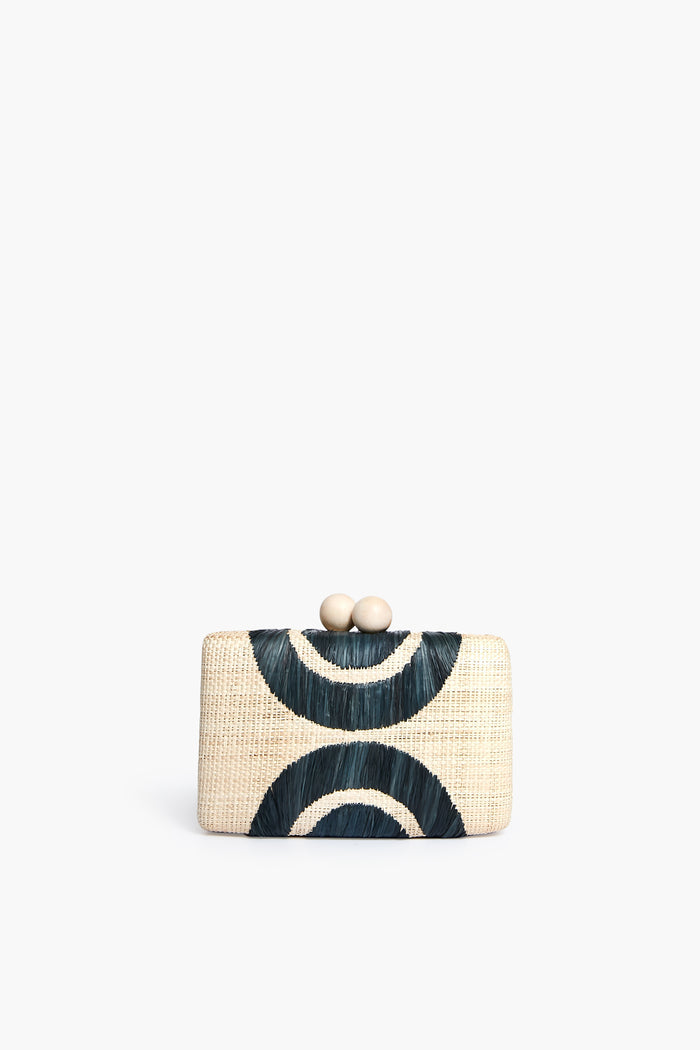The Kayu rectangular straw clutch features a geometric dark blue and cream pattern and a clasp closure with two round beige knobs. This stylish accessory is part of our sustainable collection.