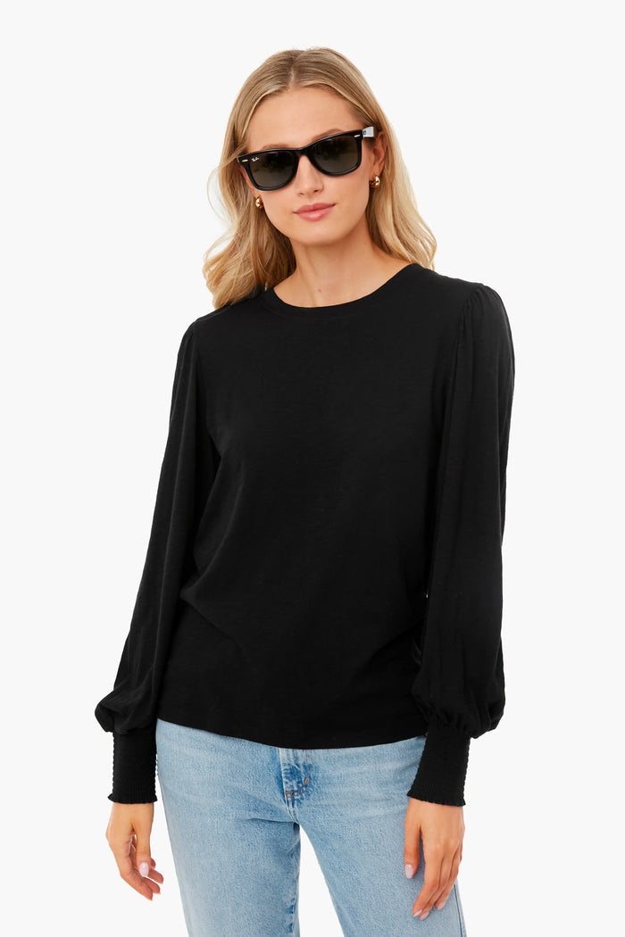 A woman wears Z SUPPLY black sunglasses and a Black Rebel Top with puffed sleeves in Brushed Slub Jersey, paired with light blue jeans. The top’s relaxed fit adds effortless style.