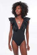 Woman wearing the Sea New York Black Siena One Piece, a swimsuit featuring a deep V-neckline and eyelet-trimmed, scalloped ruffle shoulders.