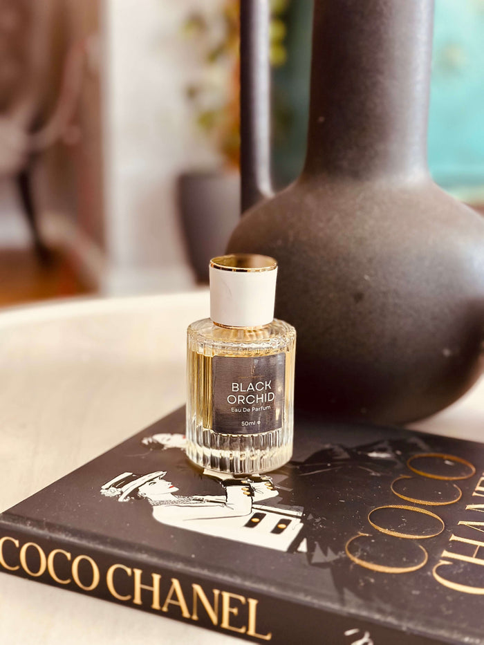 Black Truffle & Patchouli Eau de Parfum by LU Fragrances - 50ml bottle on a Coco Chanel book beside a dark ceramic vase, Tom Ford Black Orchid type