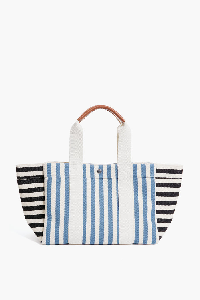 A Rue de Verneuil tote bag featuring vertical blue and white stripes in the center, horizontal black and white stripes on the sides, two white handles, and a small brown grip.