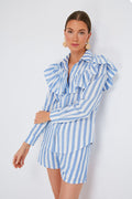 A woman wears a Clare V blue and white striped ruffle detail shirt with scallop stripes, paired with large round earrings.