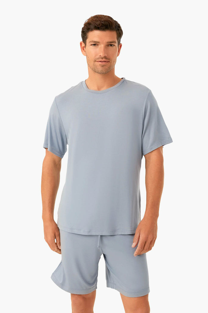 A man models Eberjey sustainable loungewear in a light blue short-sleeve shirt and matching shorts.