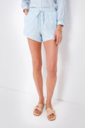 A person wears light blue and white striped TROVATA Birds of Paradis Oxford Dora Shorts, a matching striped shirt, woven beige sandals, and a gold bracelet.
