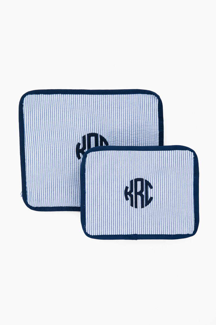 Two rectangular, blue-and-white striped fabric pouches with dark blue trim and a circular KRC monogram from Caton's Wharf—perfect as travel pouches or a thoughtful bridesmaids gift in the Blue Seersucker Travel Set.