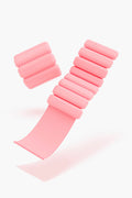 A pair of pink, adjustable Bala Bangles wearable weights from bala, made of soft silicone with cylindrical segments—ideal for adding resistance to your workout.