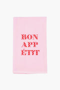 The Lynen Bon Appetit Tea Towel features light pink linen with "BON APPÉTIT" in red checkered letters at the center, adding charm to any kitchen.