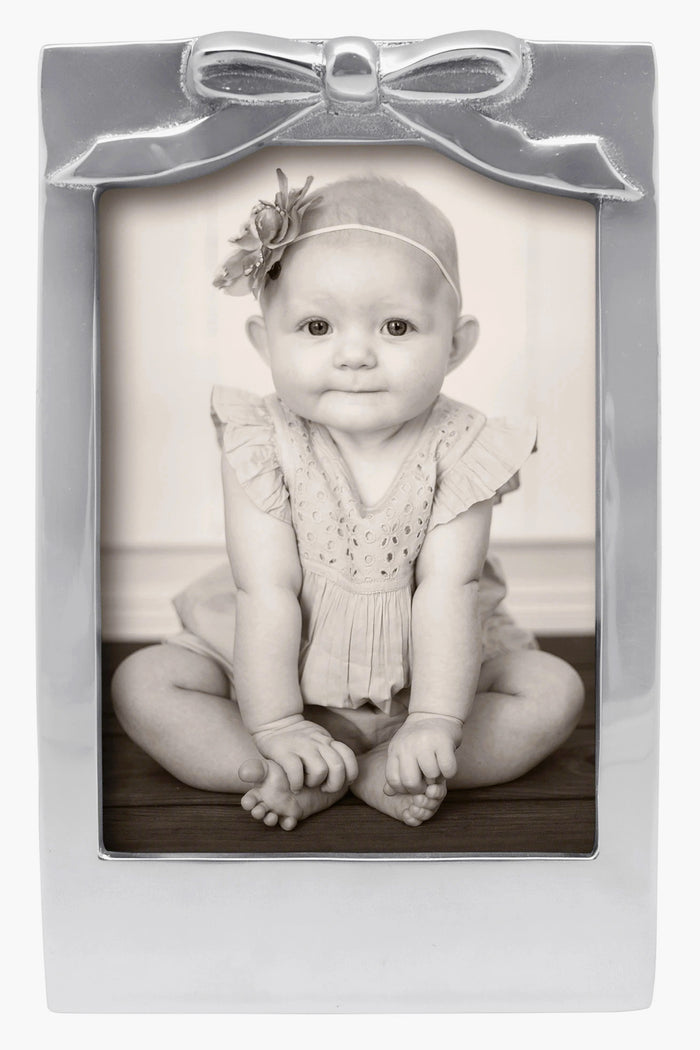 Black-and-white photo of a baby in a Mariposa 5x7 recycled aluminum frame with bow detail and flower headband—ideal as a baby shower gift.