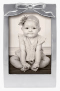 Black-and-white photo of a baby in a Mariposa 5x7 recycled aluminum frame with bow detail and flower headband—ideal as a baby shower gift.