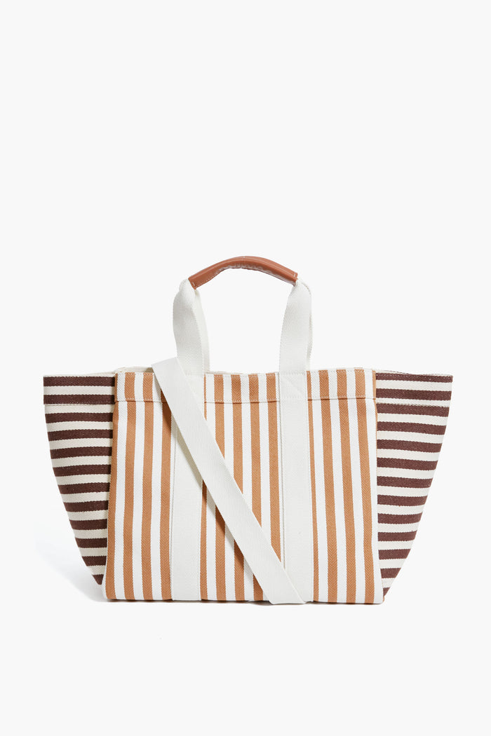 The Rue de Verneuil luxury tote bag features brown, beige, and white stripes, leather top handles with a brown grip, and a detachable shoulder strap.