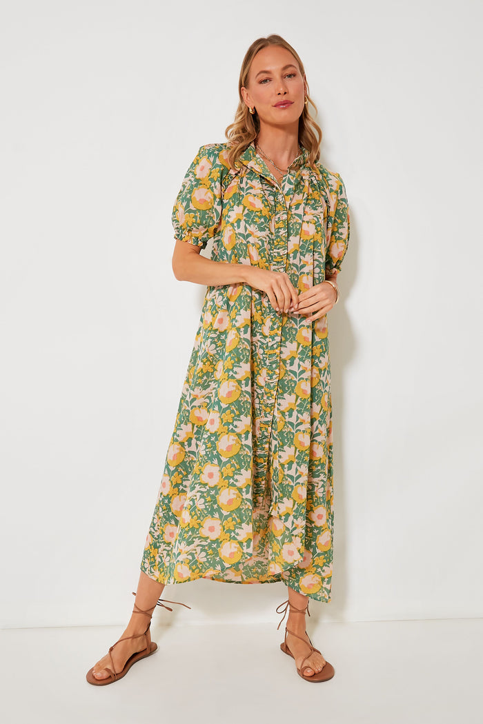 A woman wears a MIRTH green, yellow, and orange block print dress with short puff sleeves and brown flat sandals—an ideal ethical resort wear look.
