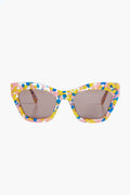 Lele Sadoughi cat-eye sunglasses showcase yellow confetti frames paired with oversized brown-tinted lenses, creating a bold and playful style.