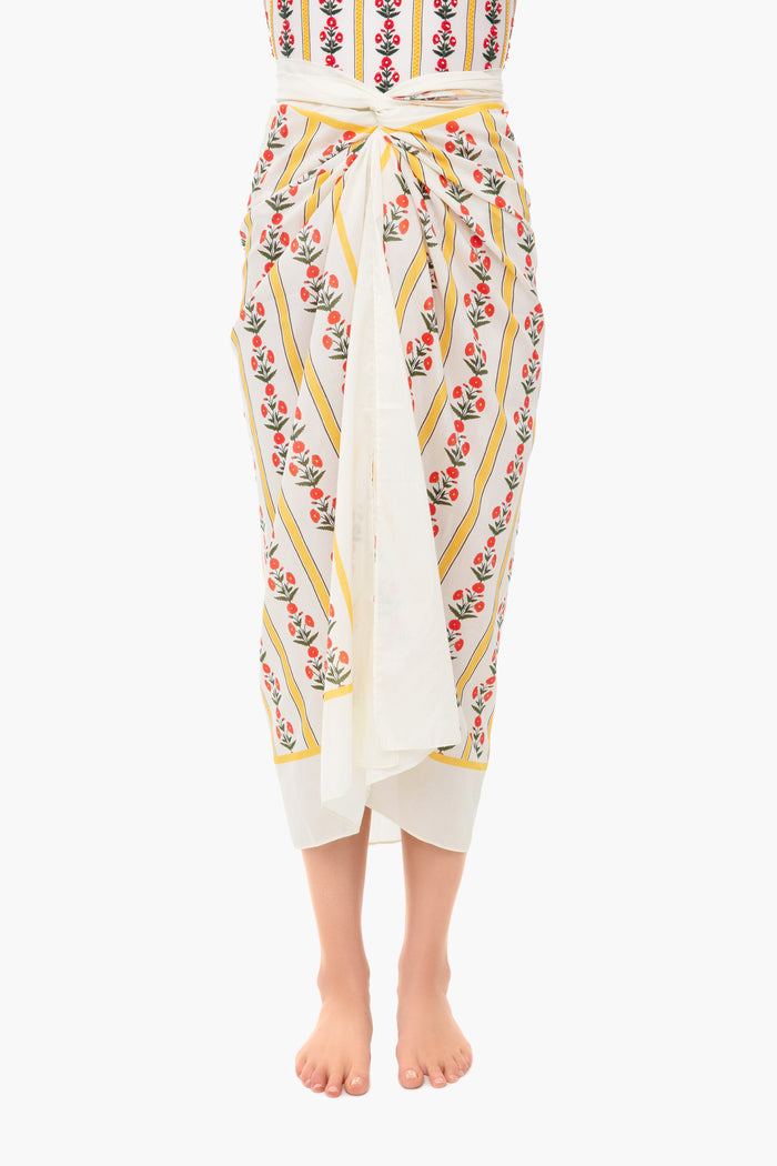 A person barefoot wearing an AGUA BY AGUA BENDITA cotton-silk sarong featuring floral and striped patterns, tied at the front.