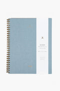 The APPOINTED Chambray Blue Lined Notebook features a spiral binding, white vertical label with gold text and accents, a durable book-cloth cover, and recycled paper.