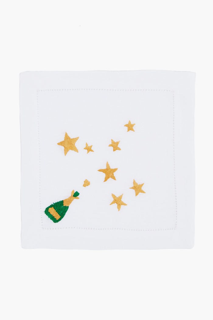 Tuckernuck Home’s white linen hemstitch napkin features embroidered gold stars and a green champagne bottle with bubbles—perfect as festive Champagne and Stars Cocktail Napkins or a stylish hostess gift.