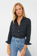 A woman with long blonde hair wears a TROVATA Birds of Paradis Plaid Blake Shirt in an oversized boyfriend fit, paired with light blue high-waisted jeans. The 100% cotton shirt features rolled sleeves for a relaxed, timeless style.