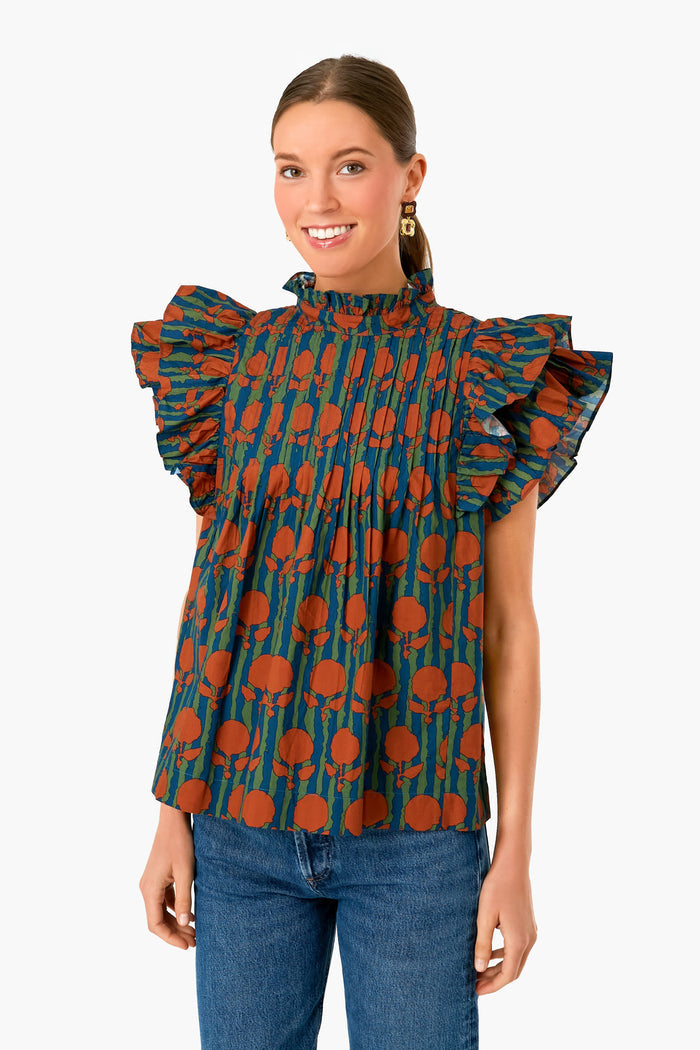 A woman models the Oliphant ruffled short-sleeve cotton blouse in an orange floral print, paired with blue jeans, in a minimalist setting.