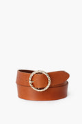 A brown cow leather belt from Loeffler Randall featuring a textured gold twisted circle buckle, coiled neatly.