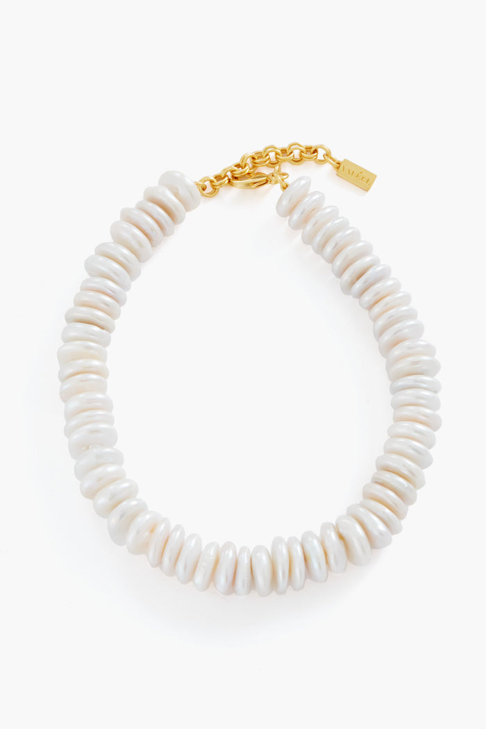 The VALERE Coin Pearl Necklace features white disc-shaped pearls, a 24k gold-plated chain, and a rectangular tag closure.