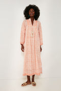 A woman wears a Marea boho-chic maxi dress with an orange geometric pattern and tan sandals, highlighting coastal-inspired fashion.