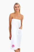A woman wears a Caton's Wharf white cotton waffle bath wrap with a pocket and pink monogram detail, making it a perfect bridal party gift.