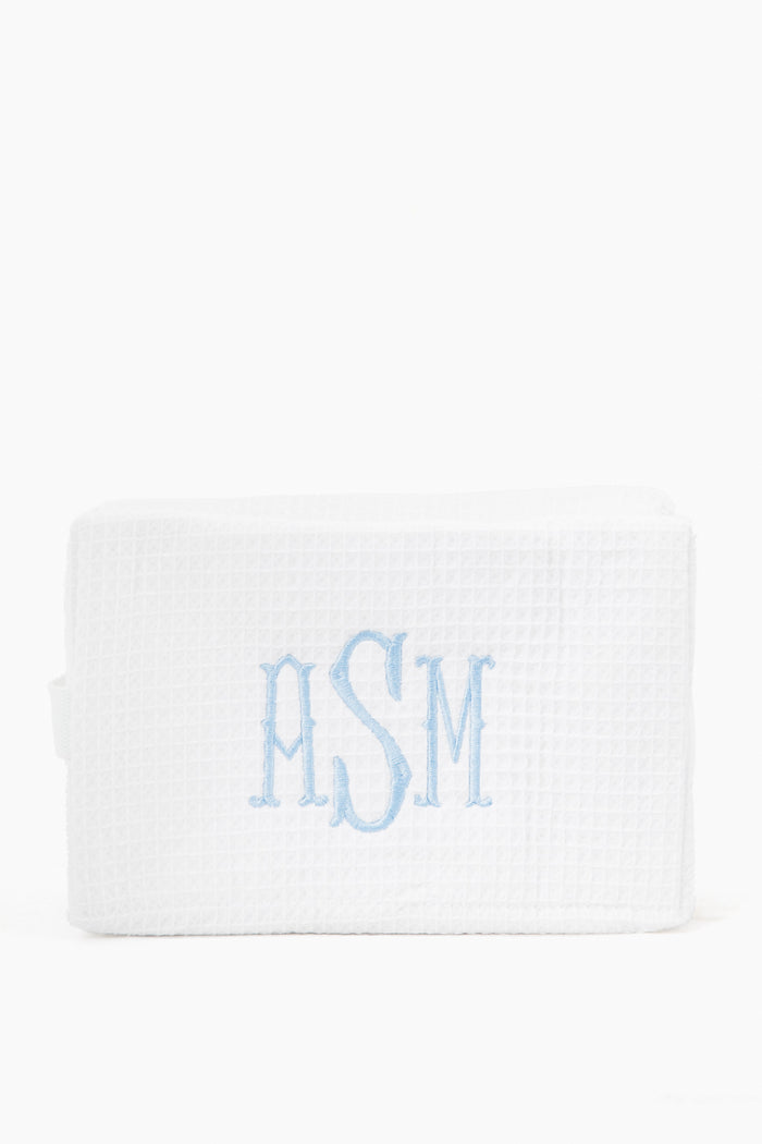 A white cotton waffle cosmetic bag by Caton's Wharf, featuring the monogram ASM embroidered in light blue on the front.