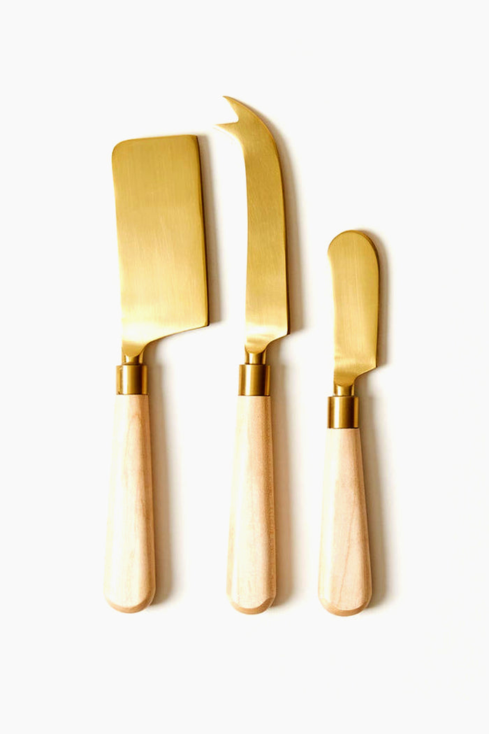 The Farmhouse Pottery, Inc cheese knife set includes three gold knives with handcrafted wooden handles, arranged side by side—perfect for adding a touch of farmhouse charm to your entertaining.